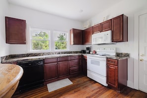 Une cuisine avec des meubles de couleur bois foncé, une cuisinière blanche et un plan de travail en granit.