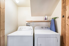 A laundry room with two white Whirlpool washers, a wooden shelf above, and a blue towel hanging on a hook. - The ONE ! Cozy Private Cabin in a Prime Location ! (Sevierville)