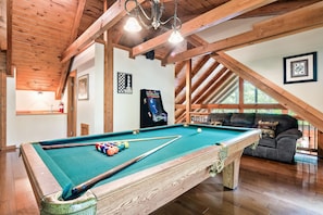 A pool table with a cue stick and balls, a sofa, and a framed chessboard in a room with wooden beams and a window. - The ONE ! Cozy Private Cabin in a Prime Location ! (Sevierville)