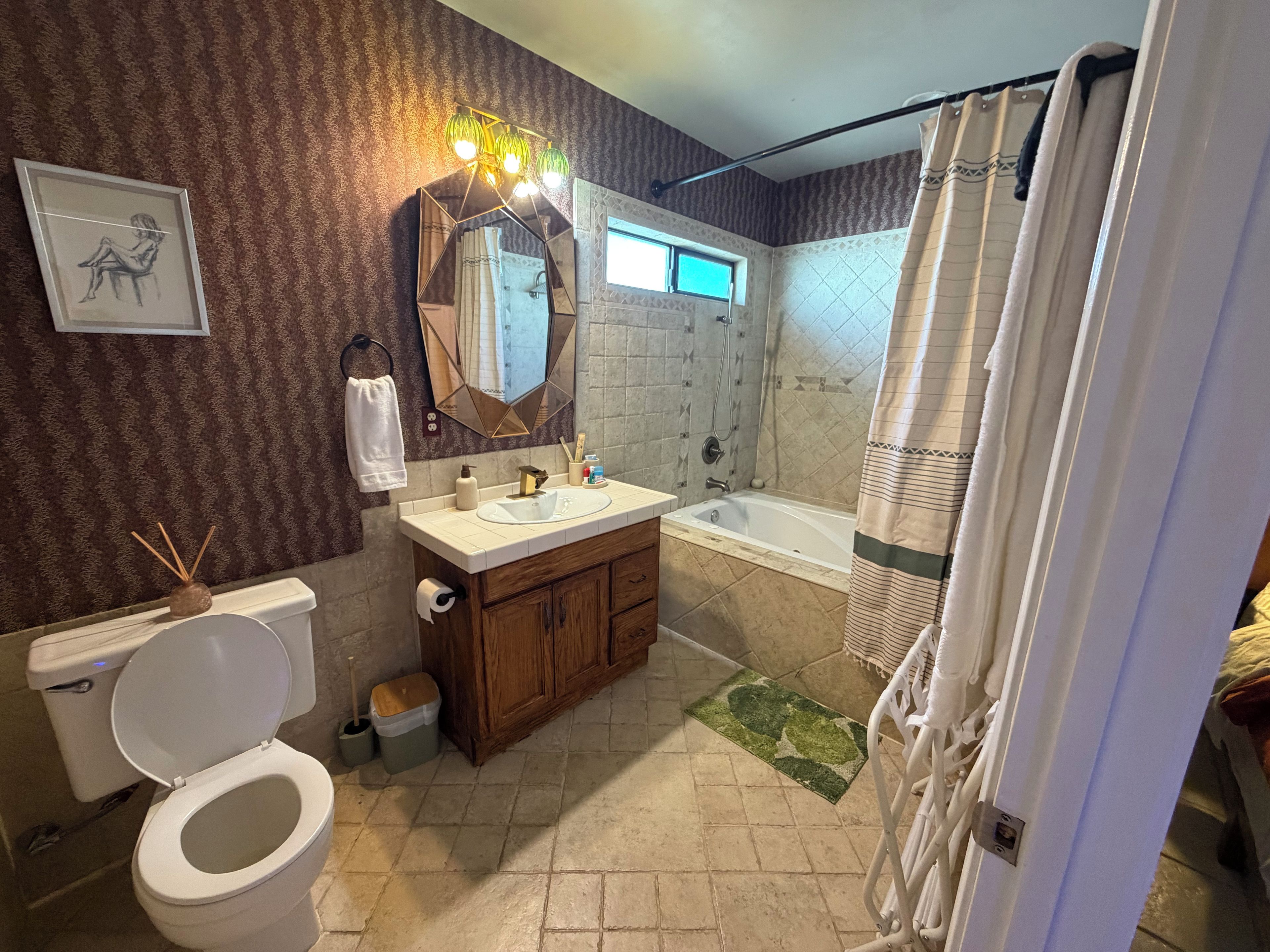 A bathroom with a toilet, sink, mirror, shower, and a towel rack.
