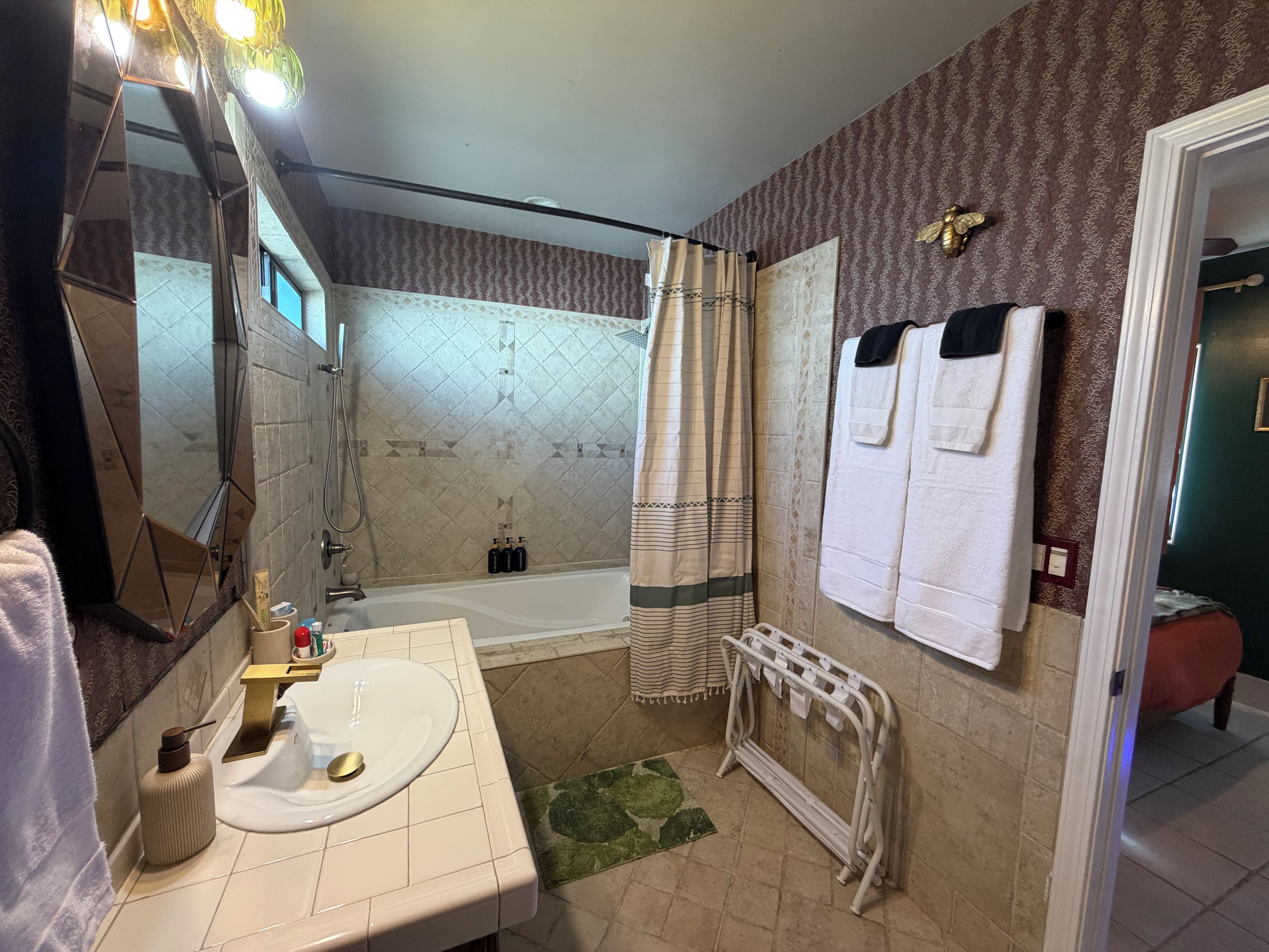 Une salle de bain avec une baignoire, un lavabo, un miroir et une douche.