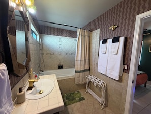 Un baño con bañera, lavamanos, espejo y ducha.
