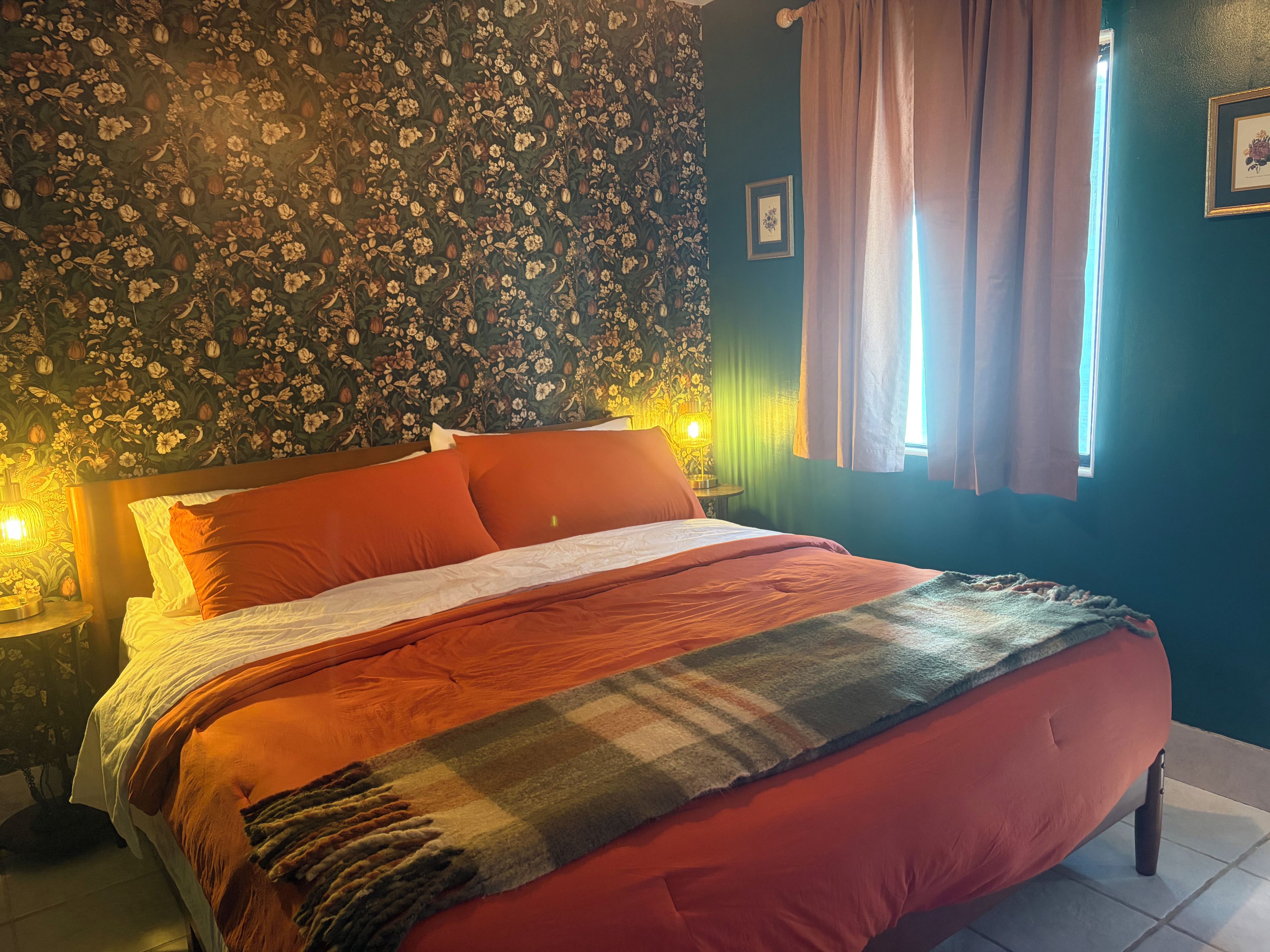 A bed with a red and white bedspread, a patterned headboard, and a nightstand with a lamp.
