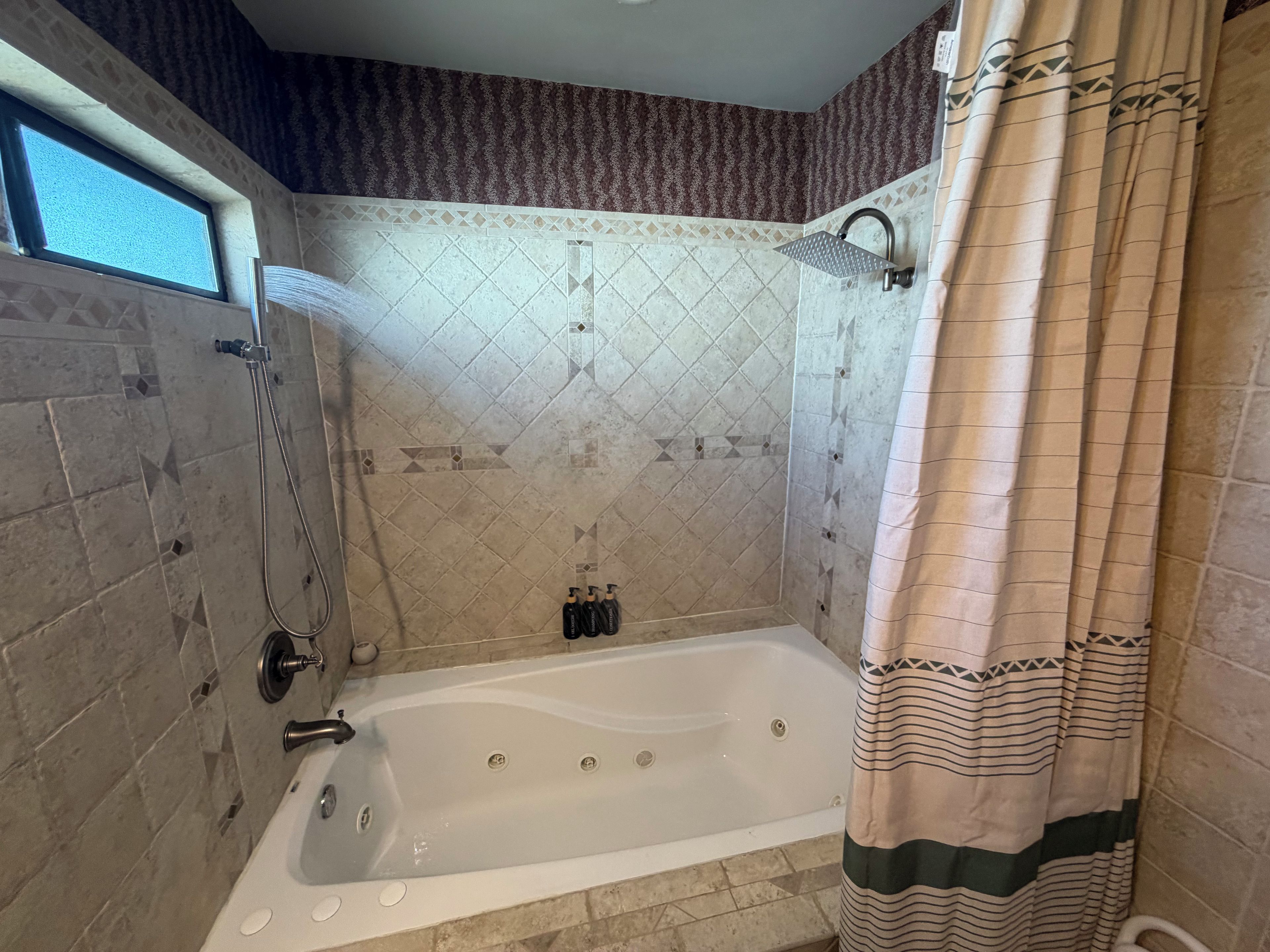 A bathroom with a bathtub, shower, and a window.