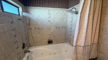 A bathroom with a bathtub, shower, and a window.