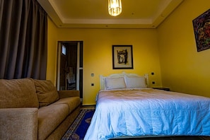 Une chambre d’hôtel avec un lit, un canapé, une porte et un tableau au mur.