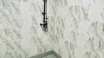 Une salle de bain avec une douche, des murs en marbre et une fenêtre.