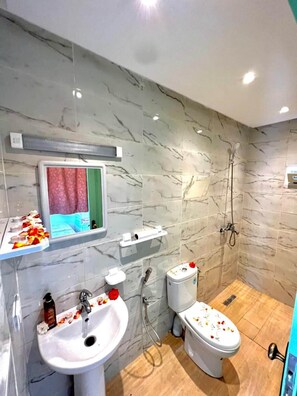 Un baño con pared de mármol, un lavabo, un inodoro y una zona de ducha.