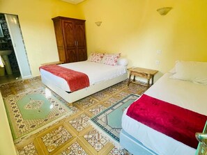 Un dormitorio con dos camas, un armario de madera y baldosas de suelo estampadas.