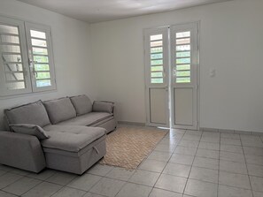 A room with a grey sectional sofa, a beige rug, and a white tiled floor. - New Listing (Sainte-Luce)