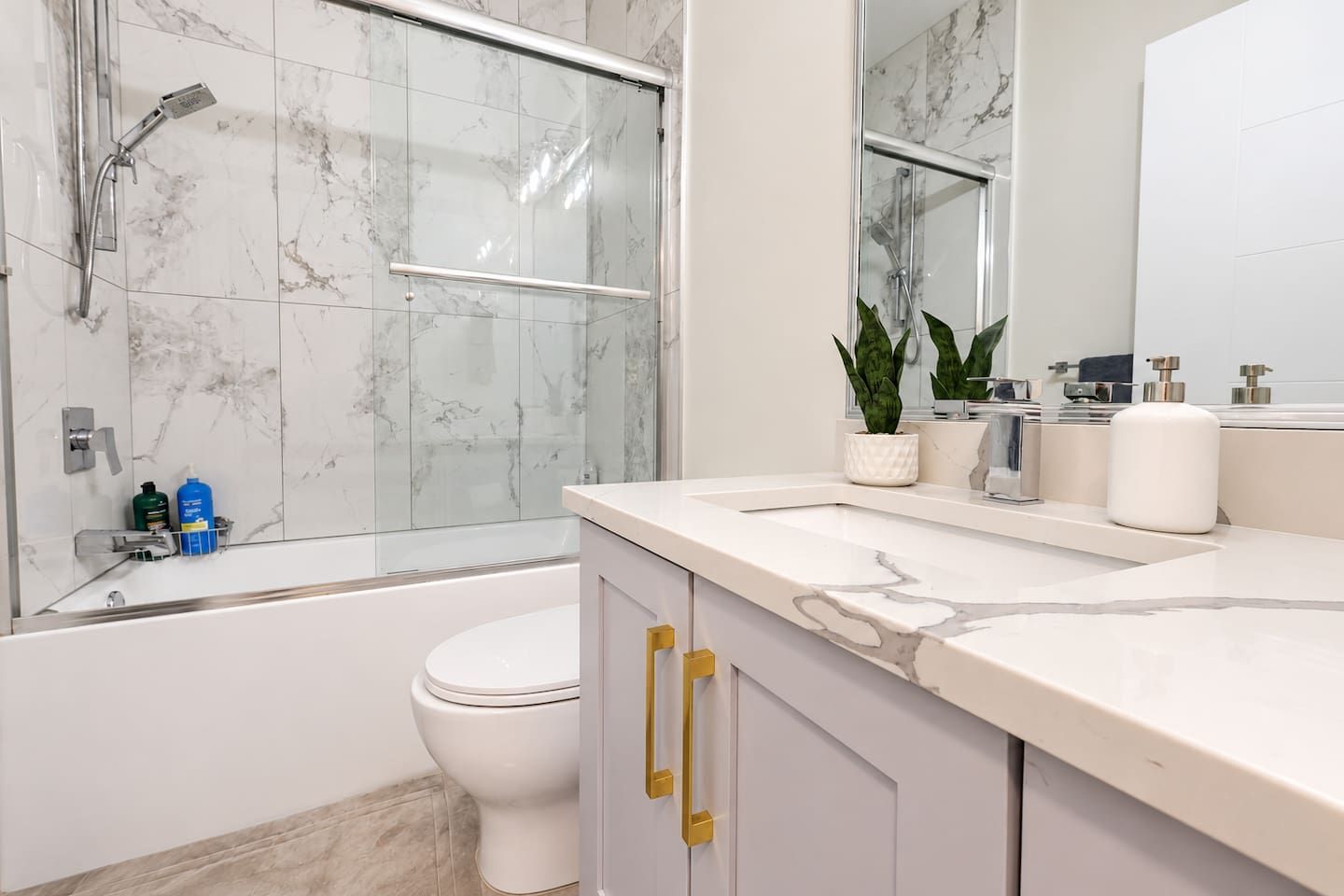 A modern bathroom with a glass shower enclosure, a white toilet, and a marble countertop.