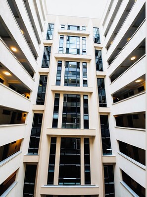 A multi-story building with a central atrium, large windows, and a symmetrical facade. - Modern 1-bedroom apartment in Roysambu, Nairobi, near TRM Mall. (Nairobi)
