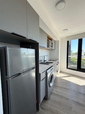 A modern kitchen with a stainless steel refrigerator, built-in oven, and washing machine. - Espectacular loft en Buceo con amenities de lujo (Montevideo)