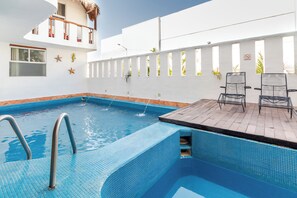 Una piscina con muelle de madera y sillas de descanso.