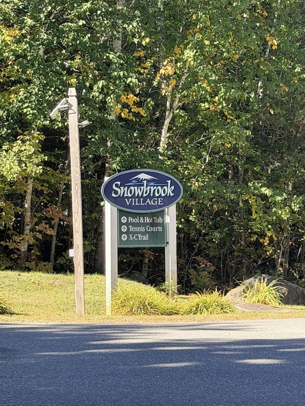 A sign for Snowbrook Village indicating amenities like a pool, hot tub, tennis courts, and an X-Ctrail.