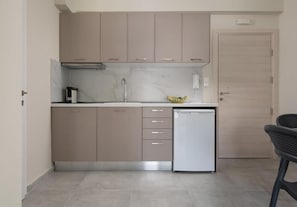 A compact kitchen with a dishwasher, cabinets, and a countertop. - Crist Luxury Apartments (Nea Potidea)
