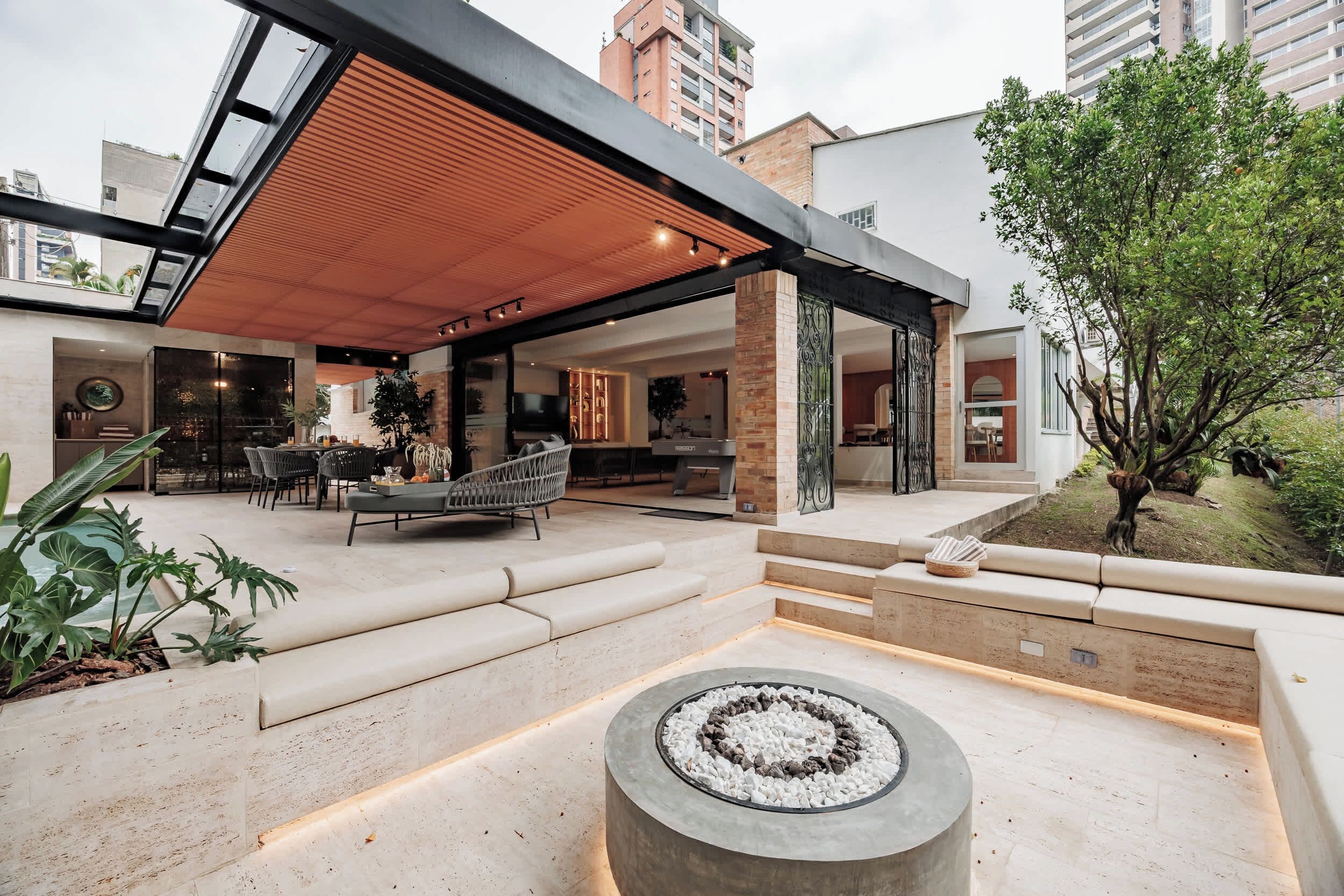 Un espacio exterior moderno con una chimenea, zona de estar y un porche cubierto.