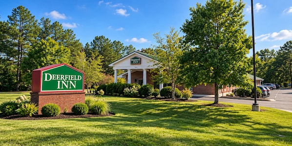 A Deerfield Inn with a brick facade, a covered front porch, and a parking lot with cars.