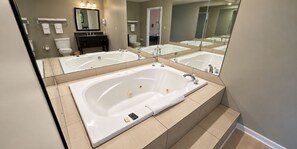 Een moderne badkamer met een vrijstaand bad, een wastafel met een spiegel en een toilet.
