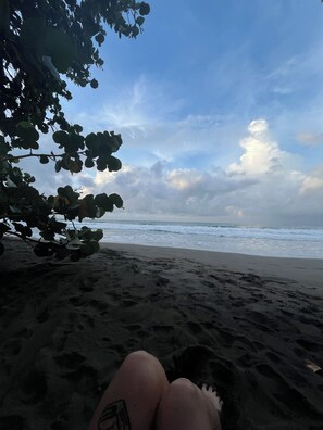 A beach scene with a person's legs and a tattoo visible, a tree branch, and the ocean. - New Listing (Puerto Viejo de Talamanca)