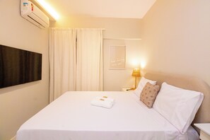A hotel room with a bed, a bedside lamp, a framed quote on the wall, and an air conditioning unit. - New Listing (Rio de Janeiro)