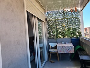 A balcony with a table and chairs, a green bench, and a decorative plant wall. - New Listing (Madrid)