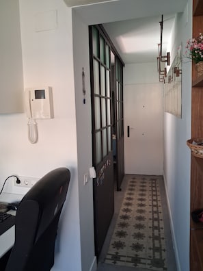 A hallway with a door, a telephone, a computer setup, and a patterned floor. - New Listing (Madrid)