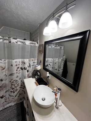 A bathroom with a white sink, a mirror, and a shower curtain with a floral pattern. - CatalpaCorner Peace-filled/Sky-Haven/Turnkey/Mid-term/Monthly/Weekly (Springfield)