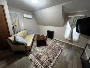 A living room with a sofa, a coffee table, a rug, a TV, and a speaker. - CatalpaCorner Peace-filled/Sky-Haven/Turnkey/Mid-term/Monthly/Weekly (Springfield)