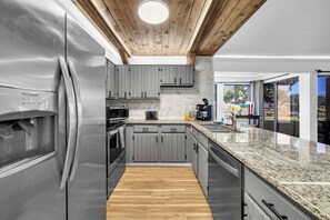 A modern kitchen with grey cabinets, stainless steel appliances, and a wooden floor. - Simply Serenity-Lakefront-Pet Friendly-Heated Pool (Destin)
