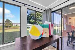 Een kamer met een groot raam, een houten tafel, een strandbal en een cadeaudoos.
