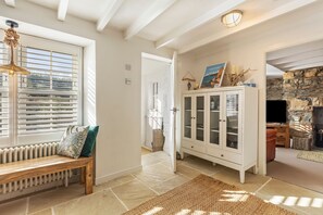 A well-lit hallway with a bench, a cabinet with glass doors, and a stone wall. - The Gables - Sea Views Rustic Country Charm (Newport)