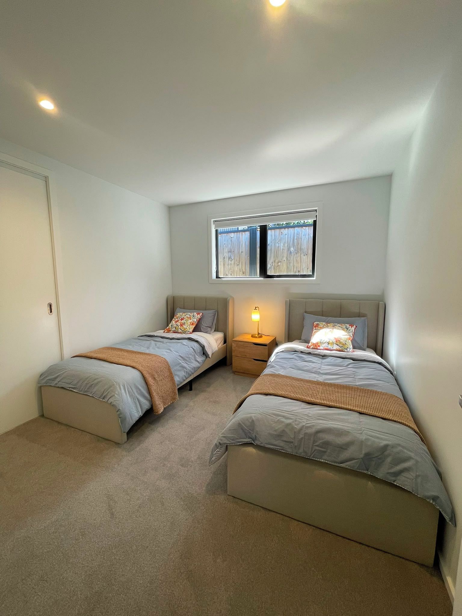 Une chambre avec deux lits, une table de chevet, une fenêtre et une porte.