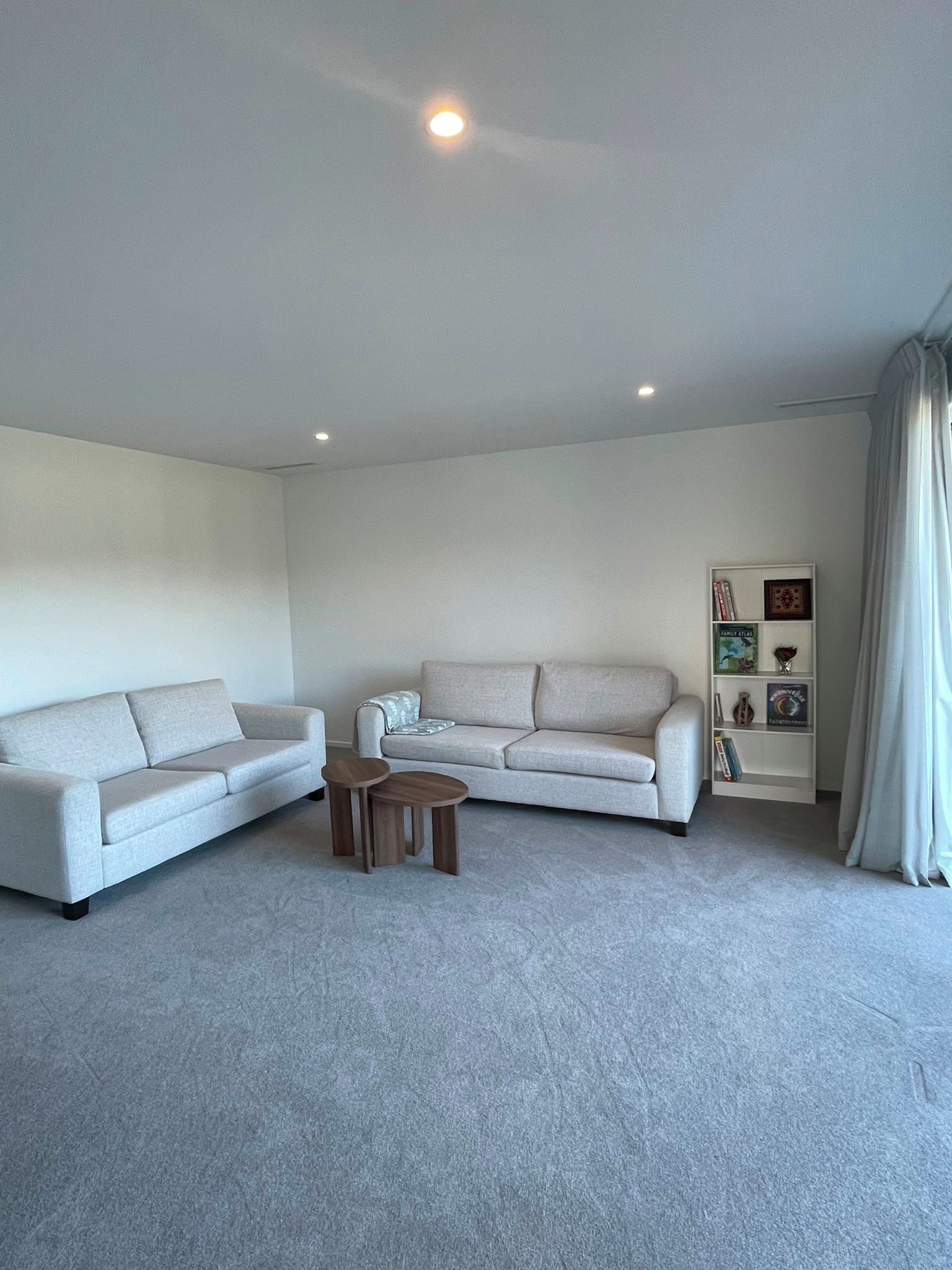 Un salon moderne avec un canapé gris, un canapé plus petit et une table basse.