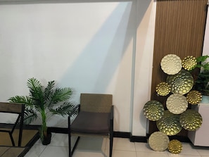 Una habitación con zona de estar, una planta en maceta y paneles decorativos en la pared.