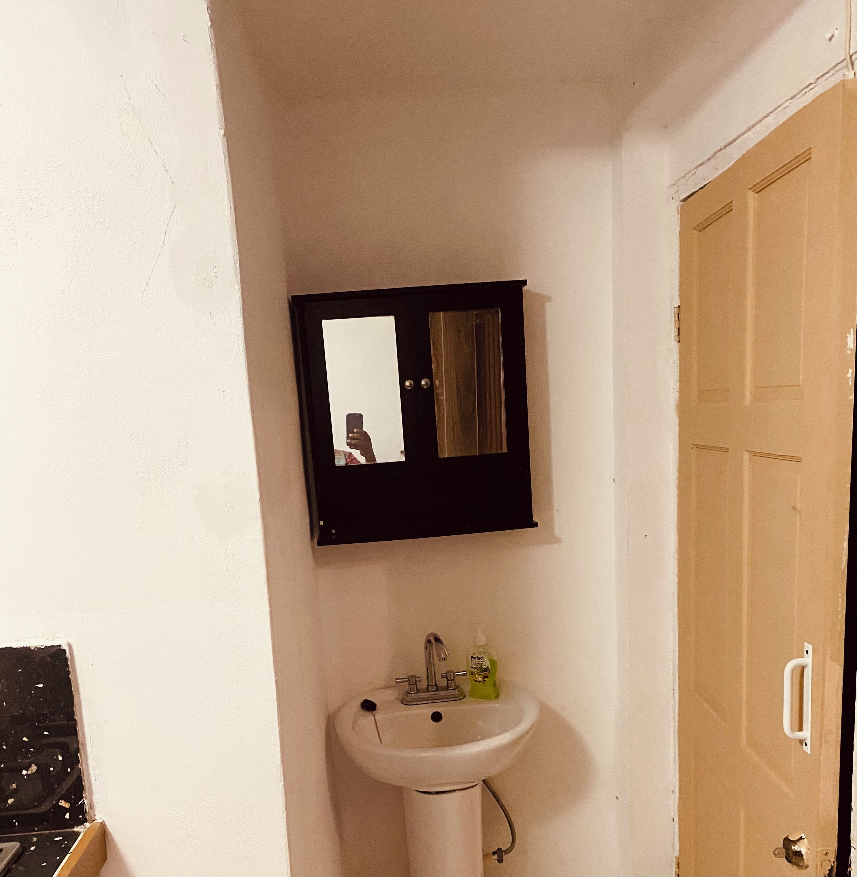 A bathroom with a white sink, a mirror, and a door.