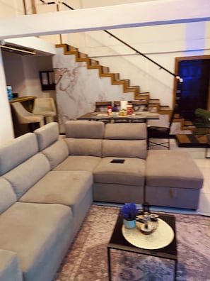 En moderne stue med en hjørnesofa, et spisebord med stole og en trappe.