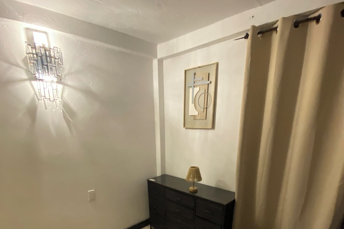 Et soveværelse med seng, kommode, lampe og et maleri på væggen.