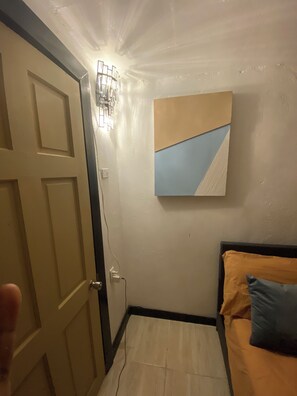 Un dormitorio con una cama, una lámpara en la pared y un cuadro.
