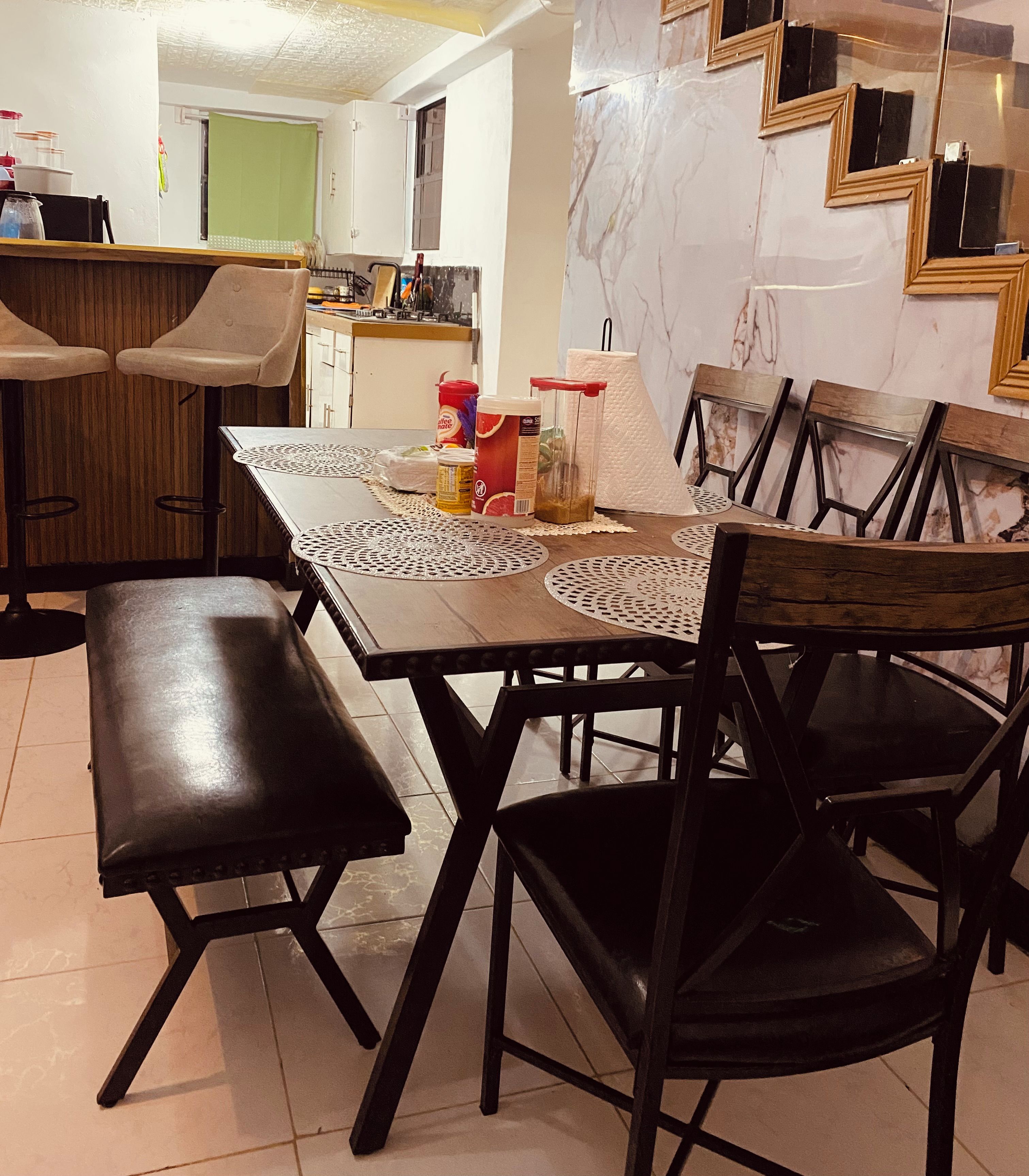 A dining area with a table set for four, surrounded by chairs, and a bench.