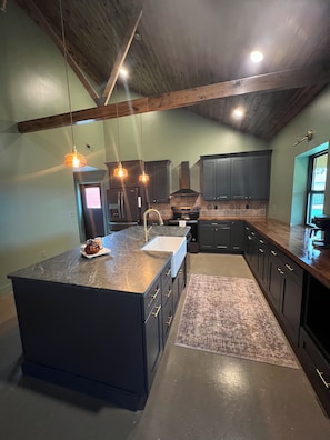A modern kitchen with a large island, dark cabinetry, and pendant lighting. - Tranquil 2-bedroom cabin with AC in charming Danville (Danville)