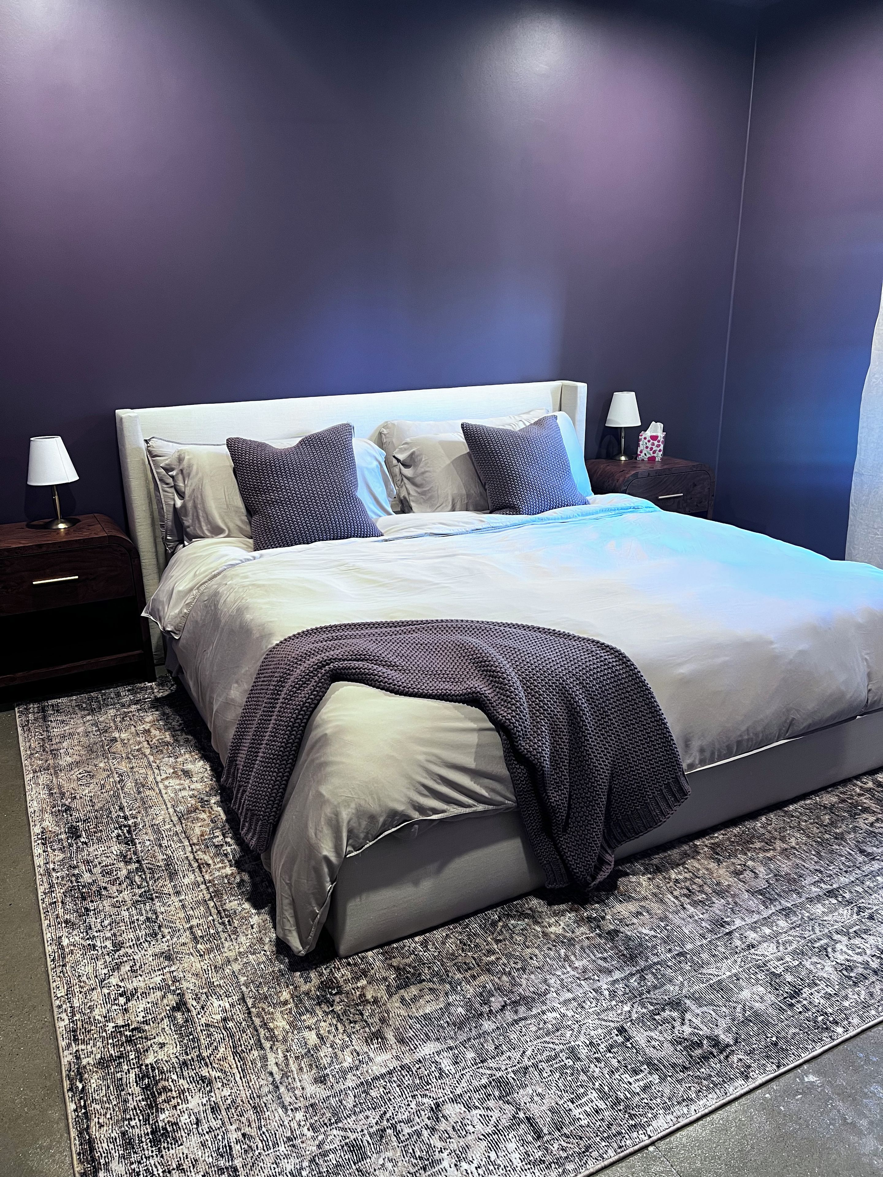 Ein modernes Schlafzimmer mit einem großen Bett, zwei Nachttischen mit Lampen und einem gemusterten Teppich.