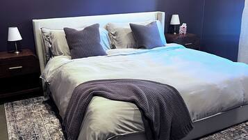 Ein modernes Schlafzimmer mit einem großen Bett, zwei Nachttischen mit Lampen und einem gemusterten Teppich.