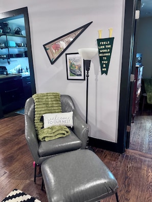 A cozy room with a leather armchair, a framed picture, a lamp, and a wall decoration. - Suite Carolyn located in the historic Mc Coy Place Lofts. (Cave City)