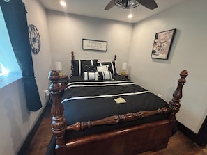 A bedroom with a four-poster bed, a clock, a framed quote on the wall, and a window with curtains. - Suite Carolyn located in the historic Mc Coy Place Lofts. (Cave City)