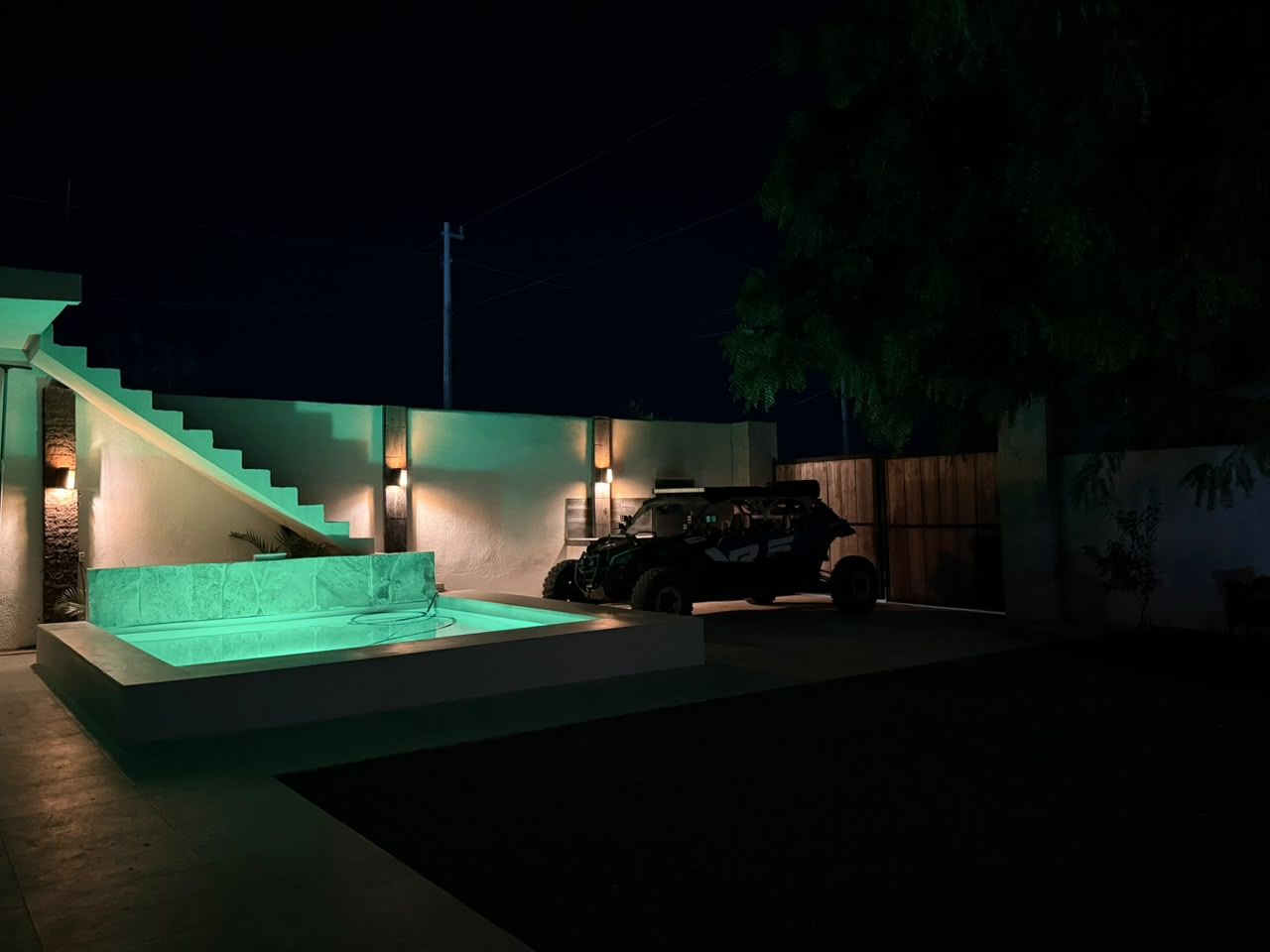 Área externa moderna com escadaria, piscina e um veículo.