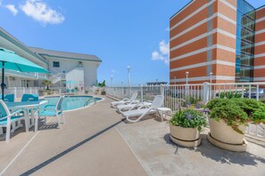 A pool area with lounge chairs and a building with a striped facade. - Oceanfront Studio: Boardwalk, Beach, & Pool Views
WiFi & Free Parking Included (Virginia Beach)