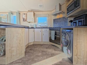A compact kitchen with a built-in oven, microwave, and washing machine. - The Alderley - Ty Mawr, Towyn, Wales (Towyn)