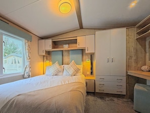 A bedroom with a bed, bedside tables, a wardrobe, and a window with curtains. - The Alderley - Ty Mawr, Towyn, Wales (Towyn)