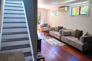 A staircase leading to a living room with a sofa, a coffee table, and a rug. - School house by the bay, beach walks, large yard, happy paws (Rippleside)
